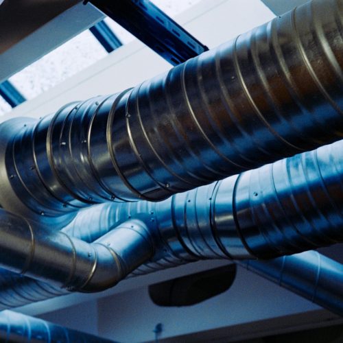Close-up of a modern metallic ventilation system in an industrial setting.