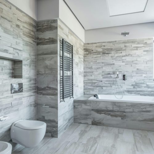 A spacious and stylish bathroom featuring modern design elements like a sleek bathtub and stone tiles.